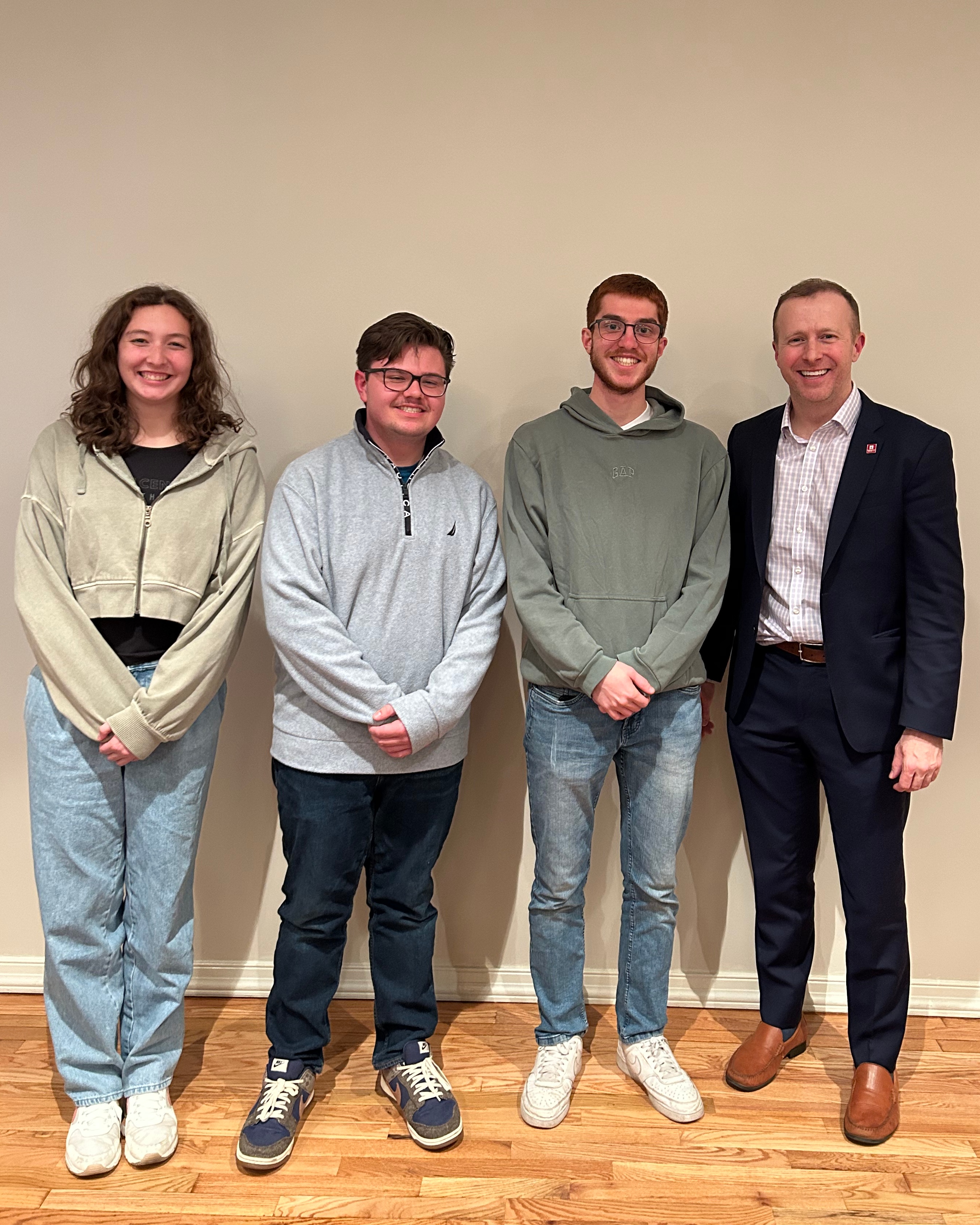 Three students and Dean David Green are posing for a photo at the Changemaker Challenge event.