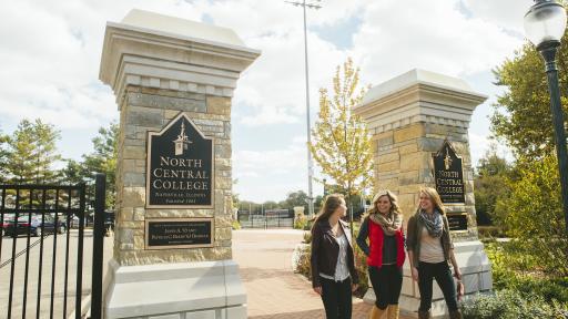 Students walking onto campus past North Central College sign
