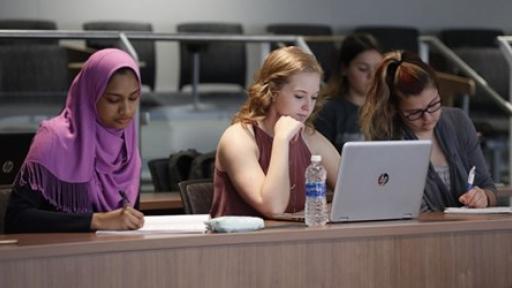 three students taking notes during class