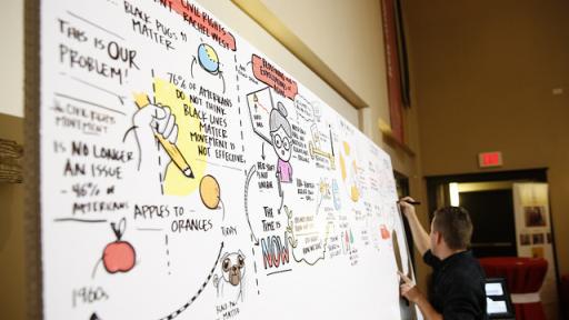 A professor creates a flowchart on a dry erase board.