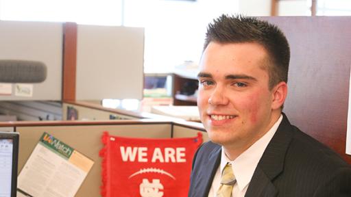 A North Central student intern showing off a We Are NC flag at their cubicle.
